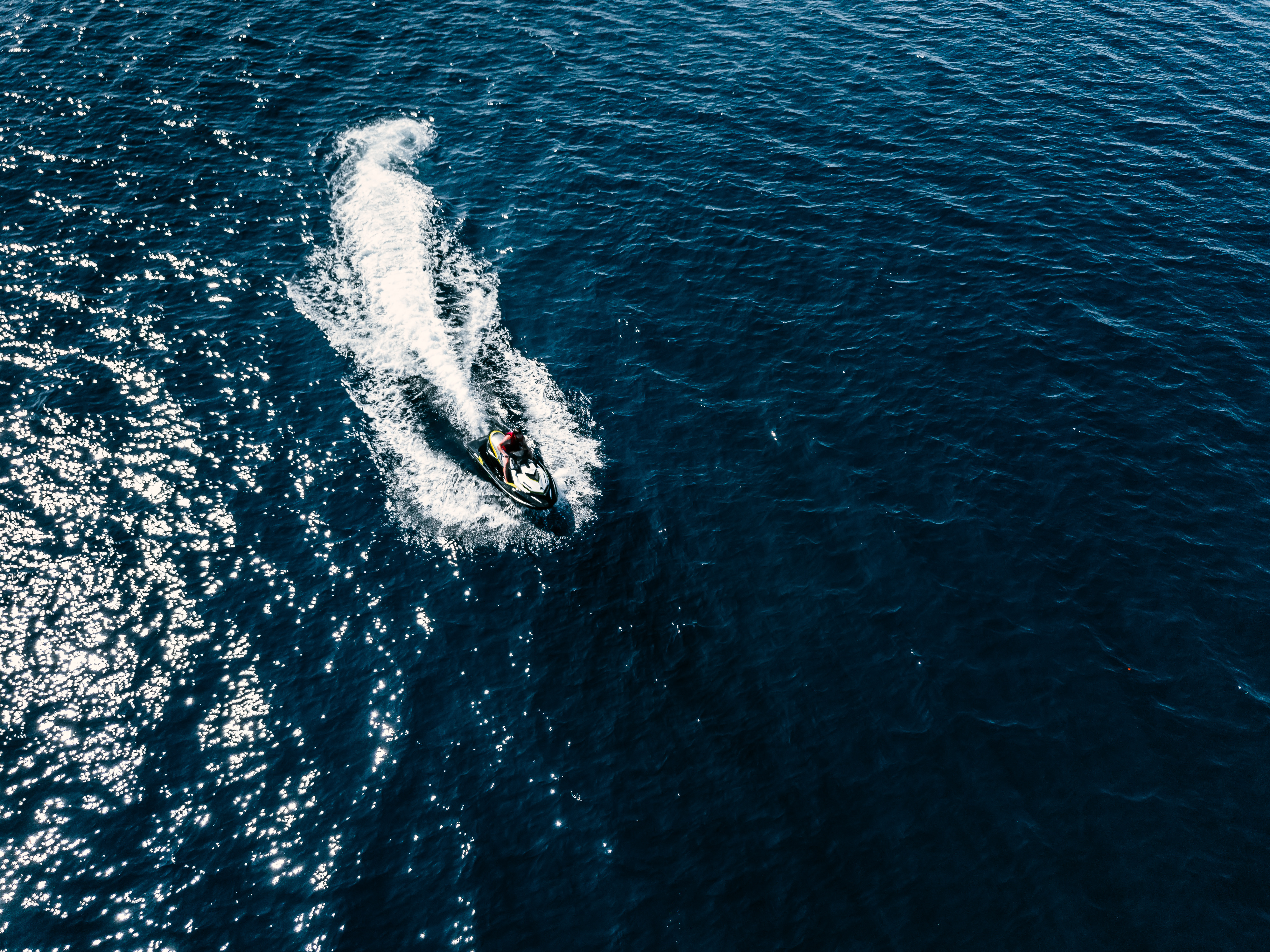 Aerial view of jet skier in blue sea. Jet ski in turquoise clear water racing